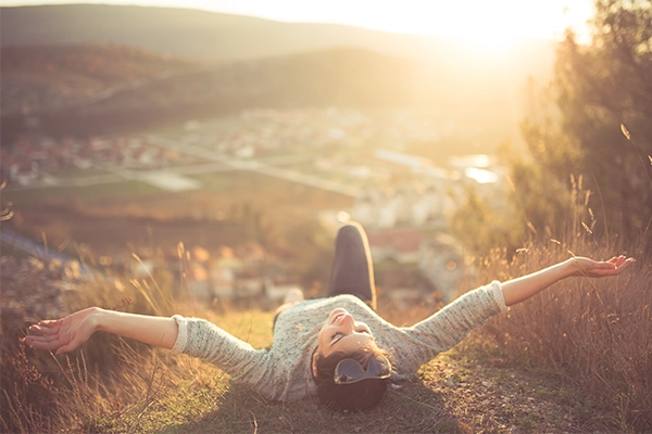 Happy woman laying on the grass outdoor to represent the contentment weight loss can bring to someone's life